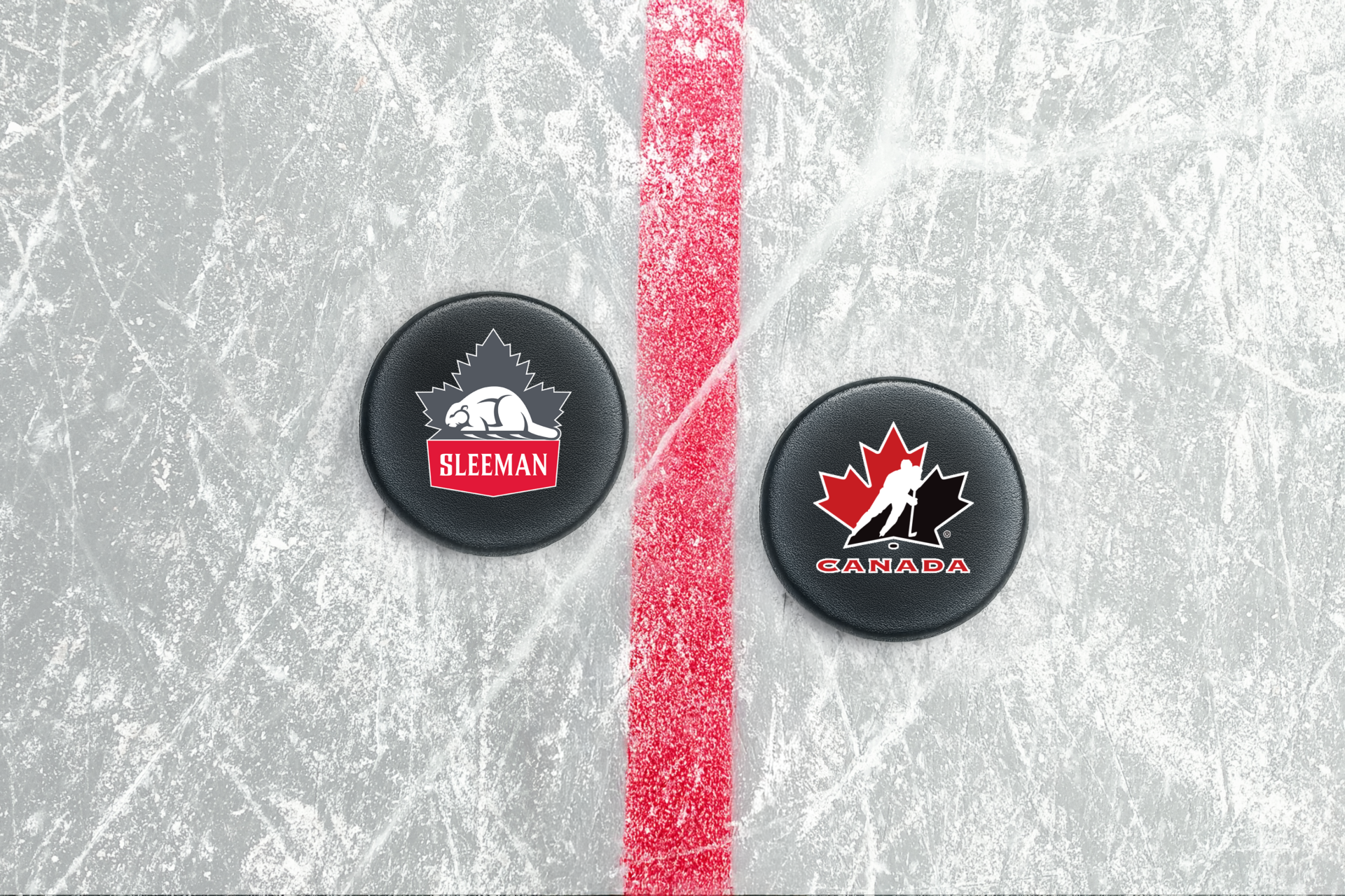 Deux rondelles au centre de la glace. L’un a le logo de la bière Sleeman et l’autre un logo de Hockey Canada.